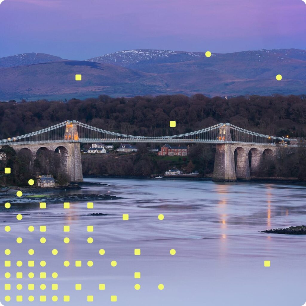 Suspension bridge over water at dusk, symbolising public investment and scientific connection.