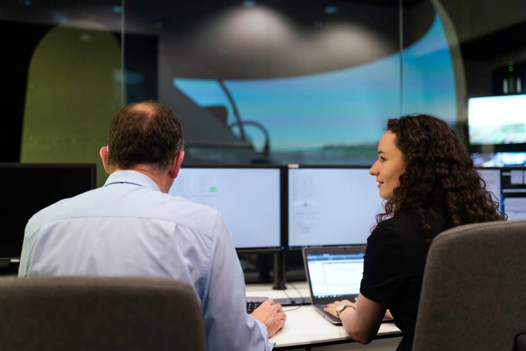 Two researchers working at a multi-monitor desktop station.